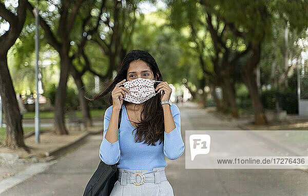 Schöne Frau  die wegschaut  während sie während der COVID-19-Pandemie eine Gesichtsschutzmaske trägt