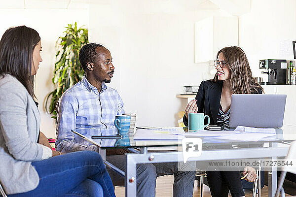 Multi-ethnische männliche und weibliche Kollegen diskutieren während einer Besprechung in einem Coworking-Büro