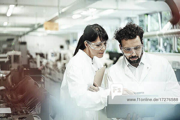 Männliche und weibliche Wissenschaftler diskutieren über Laptops im Labor