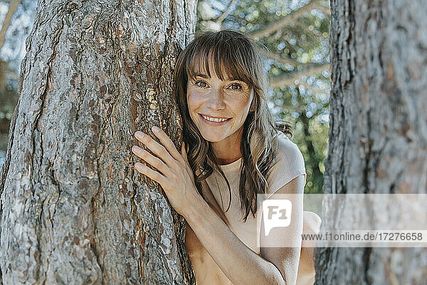 Mature woman leaning on pine tree in public park