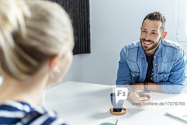 Lächelnder Mann im Gespräch mit einer Frau bei einem Kaffee im Büro