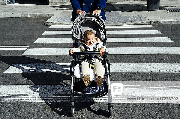 Vater mit lächelndem Baby im Kinderwagen beim Überqueren der Straße in der Stadt
