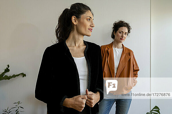 Weibliche Modelle mit Jacke  die zu Hause an der Wand stehen