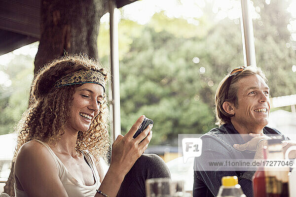 Junge Frau schreibt SMS auf ihrem Smartphone  während sie mit einem Mann in einem Cafe sitzt