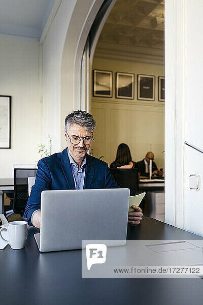 Smiling businessman working on laptop at office desk