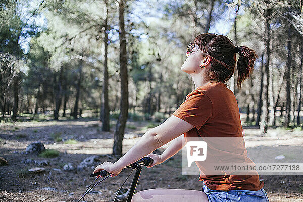 Young woman riding bicycle in countryside during weekend
