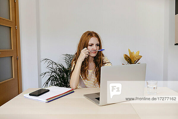 Nachdenkliche Frau  die bei der Arbeit zu Hause einen Laptop benutzt