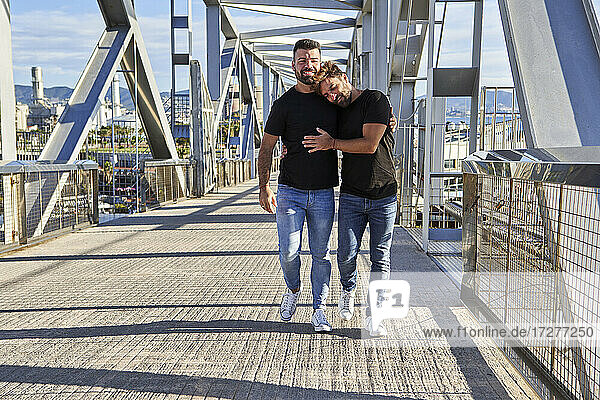 Schwuler Mann lehnt sich beim Gehen auf der Fußgängerbrücke an die Schulter seines Freundes