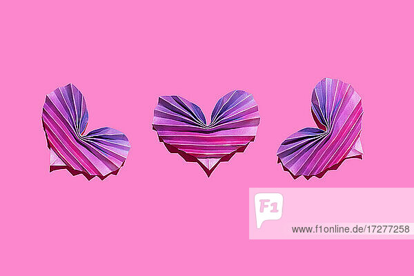Studio shot of three pink and purple origami hearts
