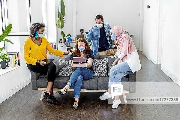Employees wearing face mask maintaining social distance while working at office during COVID-19