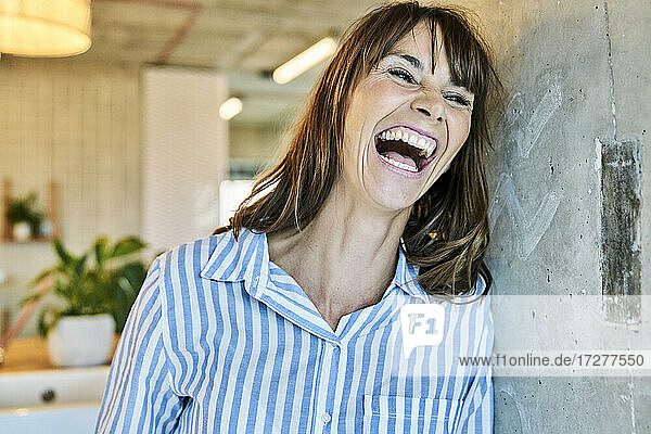 Frau lachend  während sie sich zu Hause an die Wand lehnt