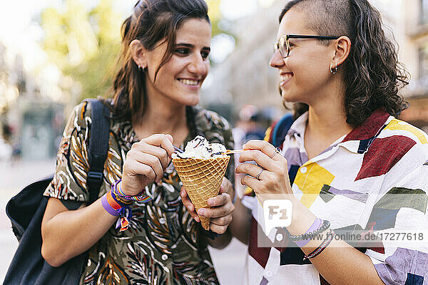 Lesbisches Paar hält Eistüte in der Hand  während es in der Stadt steht