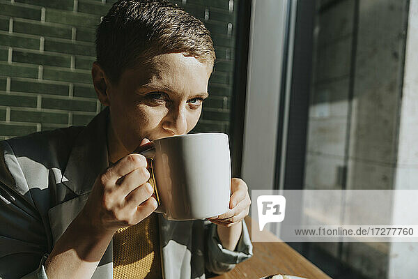 Frau trinkt Kaffee  während sie in einem Café an einem sonnigen Tag sitzt