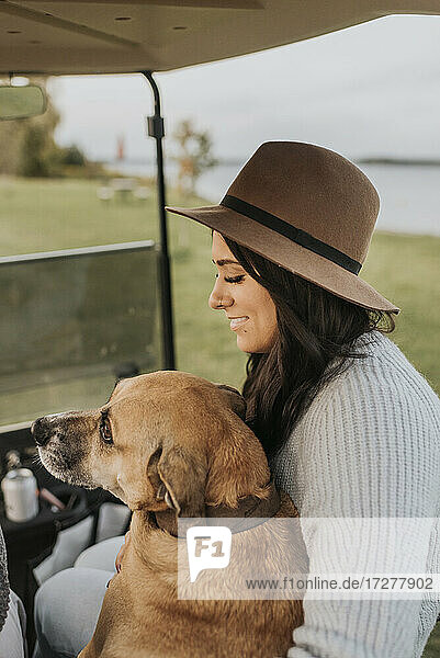 Frau lächelt  während sie mit Hund im Golfwagen sitzt
