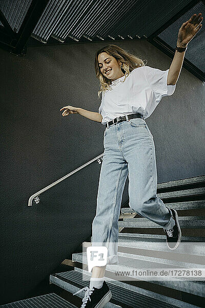 Fröhliche junge Frau läuft auf einer Treppe