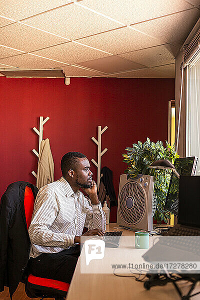 Konzentrierter junger Geschäftsmann arbeitet am Computer am Schreibtisch im Coworking-Büro