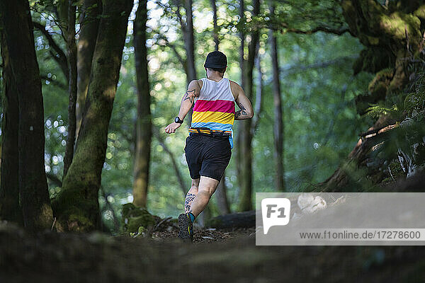 Trailrunner läuft auf dem Pfad eines Berges im Wald
