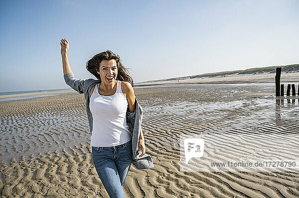 Glückliche junge Frau  die an einem sonnigen Tag am Strand spazieren geht