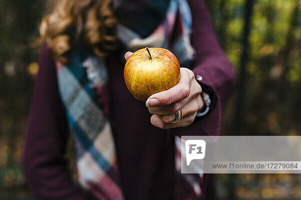 Frau zeigt Apfel im Herbst