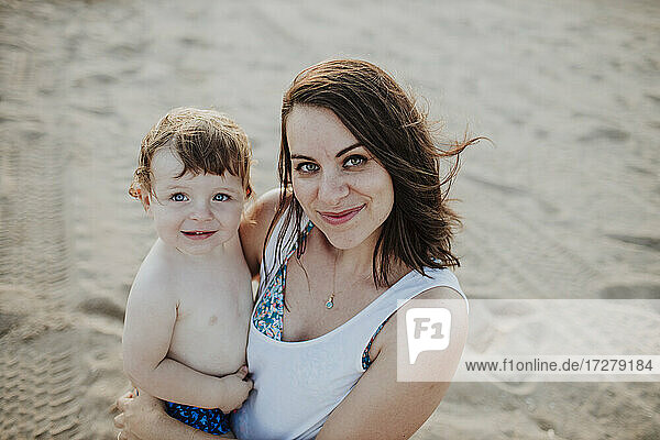 Lächelnde Mutter mit Sohn am Strand stehend
