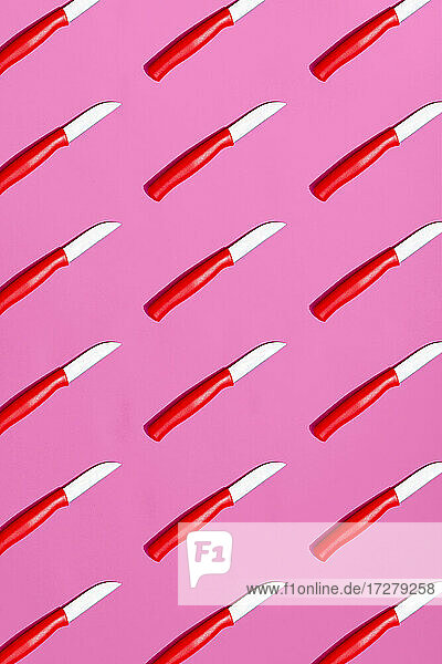 Large group of table knives on pink background