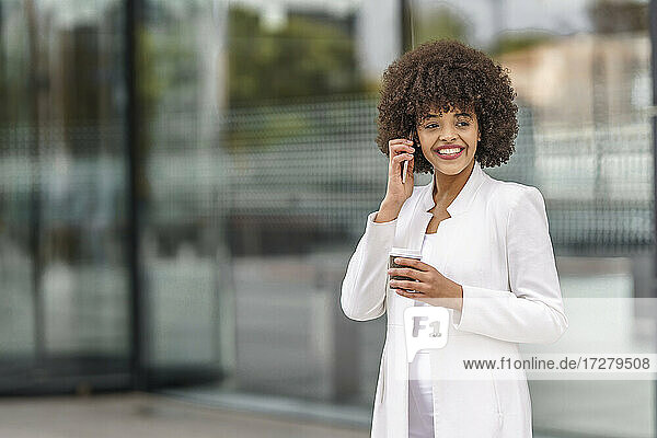 Lächelnde Geschäftsfrau  die im Freien stehend mit ihrem Handy telefoniert
