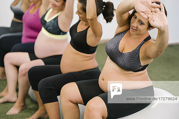 Midsection der schwangeren Frau tun Stretching-Übung beim Sitzen auf Fitness-Ball