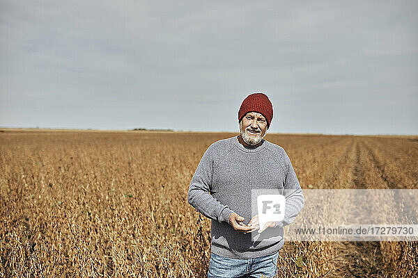 Landwirt mit Strickmütze auf einem Sojabohnenfeld bei klarem Himmel