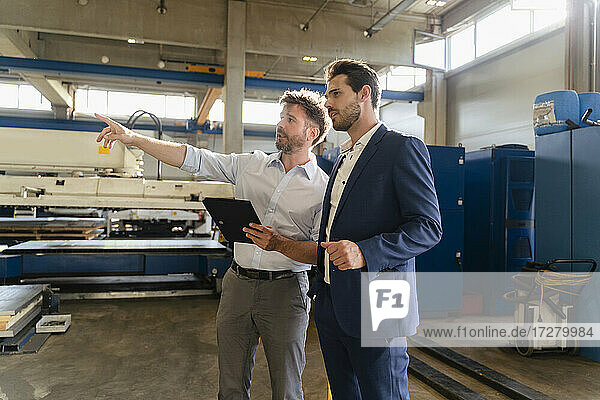 Businessman holding digital tablet working while standing by businessman at factory