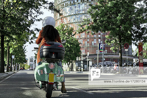 Junge Frau fährt Motorroller in der Stadt an einem sonnigen Tag