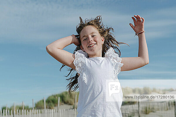 Mädchen mit Hand im Haar am Strand stehend an einem sonnigen Tag