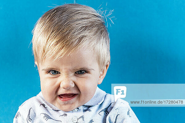 Lächelnder kleiner Junge an blauer Wand stehend