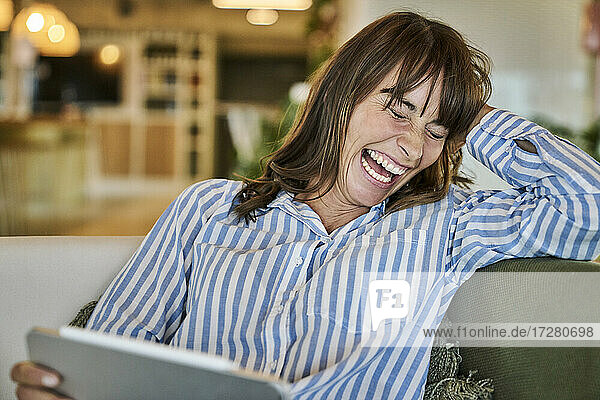 Frau lachend bei der Verwendung eines digitalen Tablets zu Hause