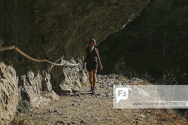 Woman looking away while walking by rock formation