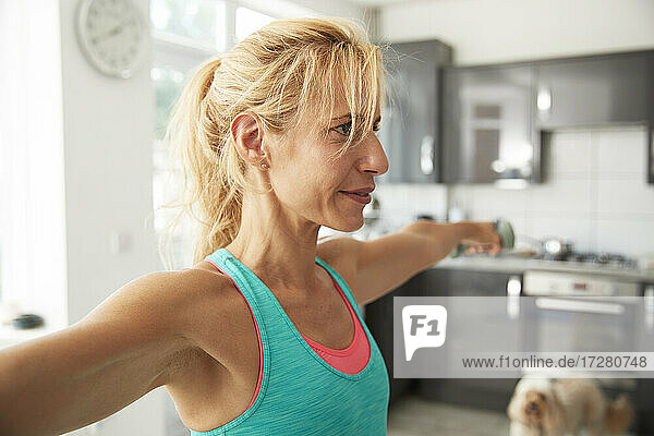 Mature woman with arms outstretched exercising at home
