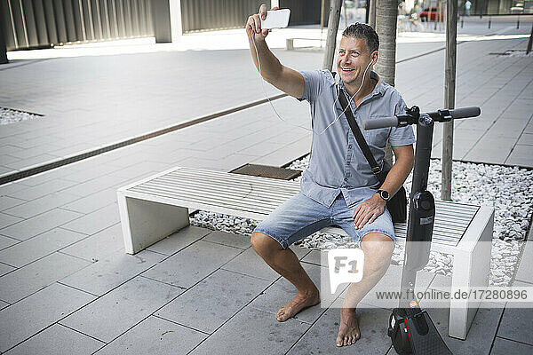 Reifer Mann  der ein Selfie macht  während er auf einer Bank sitzt
