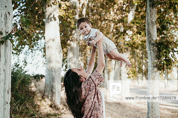 Glückliche Mutter  die mit ihrem kleinen Jungen spielt  während sie im Freien steht