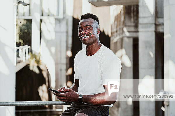 Male athlete using smart phone looking away while sitting