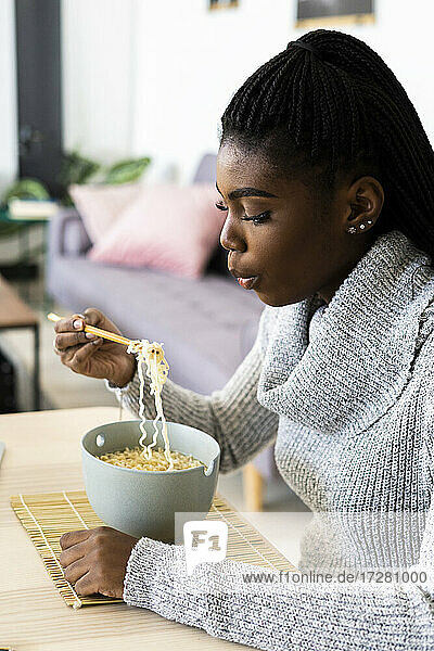 Frau isst Nudeln  während sie zu Hause sitzt