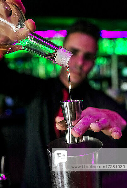 Mittlerer Erwachsener Barkeeper gießt Alkohol in ein Glas an der Bar