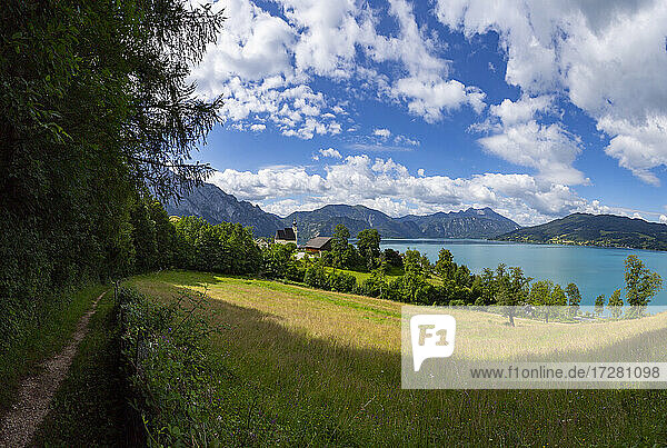 Austria  Upper Austria  Steinbach am Attersee  Footpath stretching along edge of countryside meadow in summer with Lake Atter in background