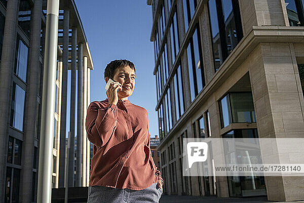 Geschäftsfrau  die mit einem Mobiltelefon telefoniert  während sie in der Stadt steht