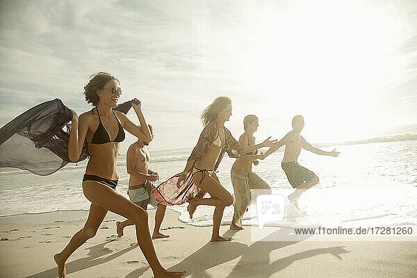 Gruppe von Freunden läuft am Strand an einem sonnigen Tag
