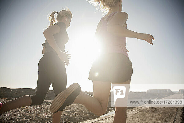 Female friends running on beach during sunny day