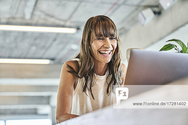 Frau lächelt  während sie einen Laptop zu Hause benutzt