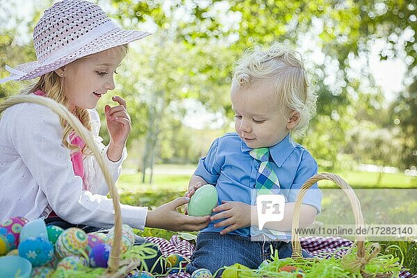 Nette junge Bruder und Schwester genießen ihre Ostereier draußen im Park zusammen