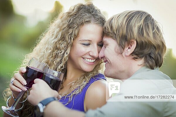 Ein attraktives Paar  das gemeinsam ein Glas Wein im Park genießt