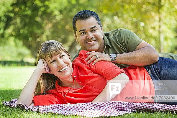 Happy attractive mixed-race couple portrait on a blanket at the park