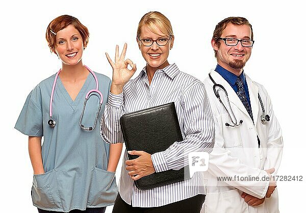 Geschäftsfrau macht okay Handzeichen mit zwei Ärzten oder Krankenschwestern vor einem weißen Hintergrund