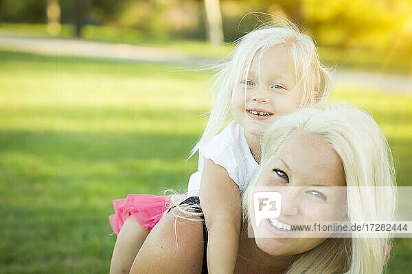 Hübsche Mutter und kleines Mädchen haben Spaß zusammen im Gras